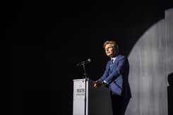 Minister Ruben Brekelmans tegen donkere achtergrond achter katheder.