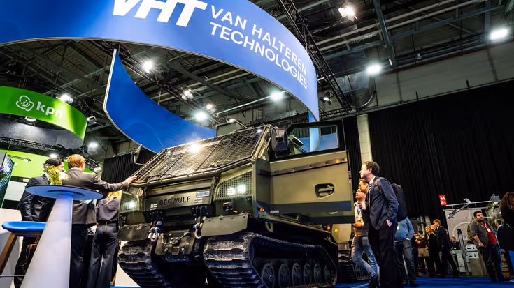 Een pantservoertuig op de beursvloer met 5 bewonderaars er omheen. 