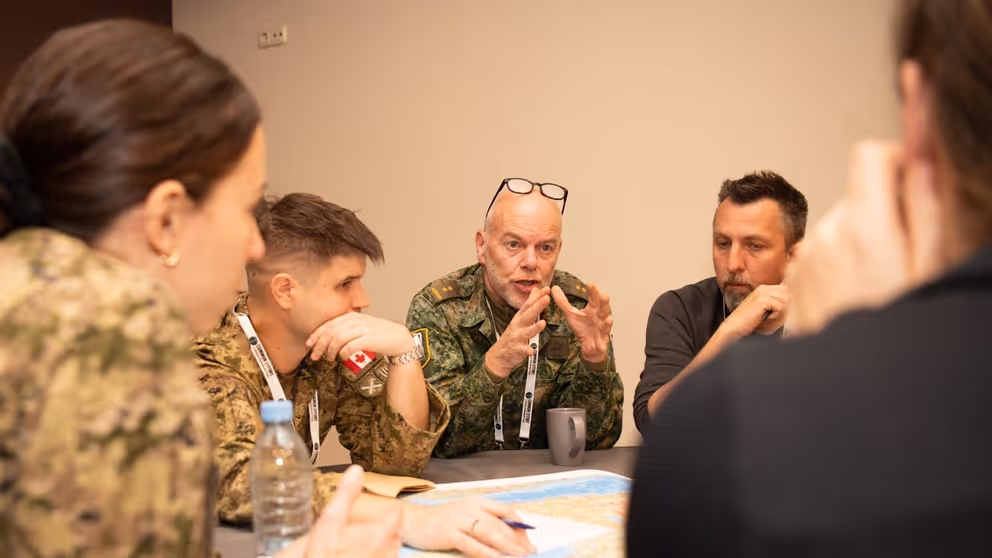 Militairen in gesprek aan een tafel.