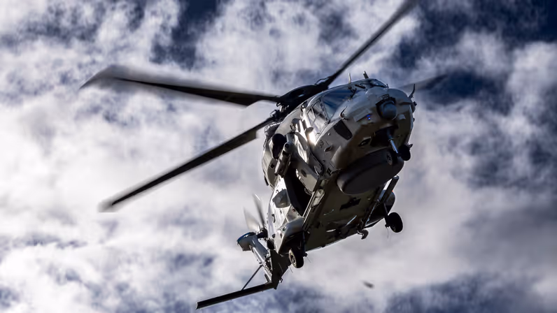 NH90 schuin van onderen tegen een blauwe lucht met bewolking.