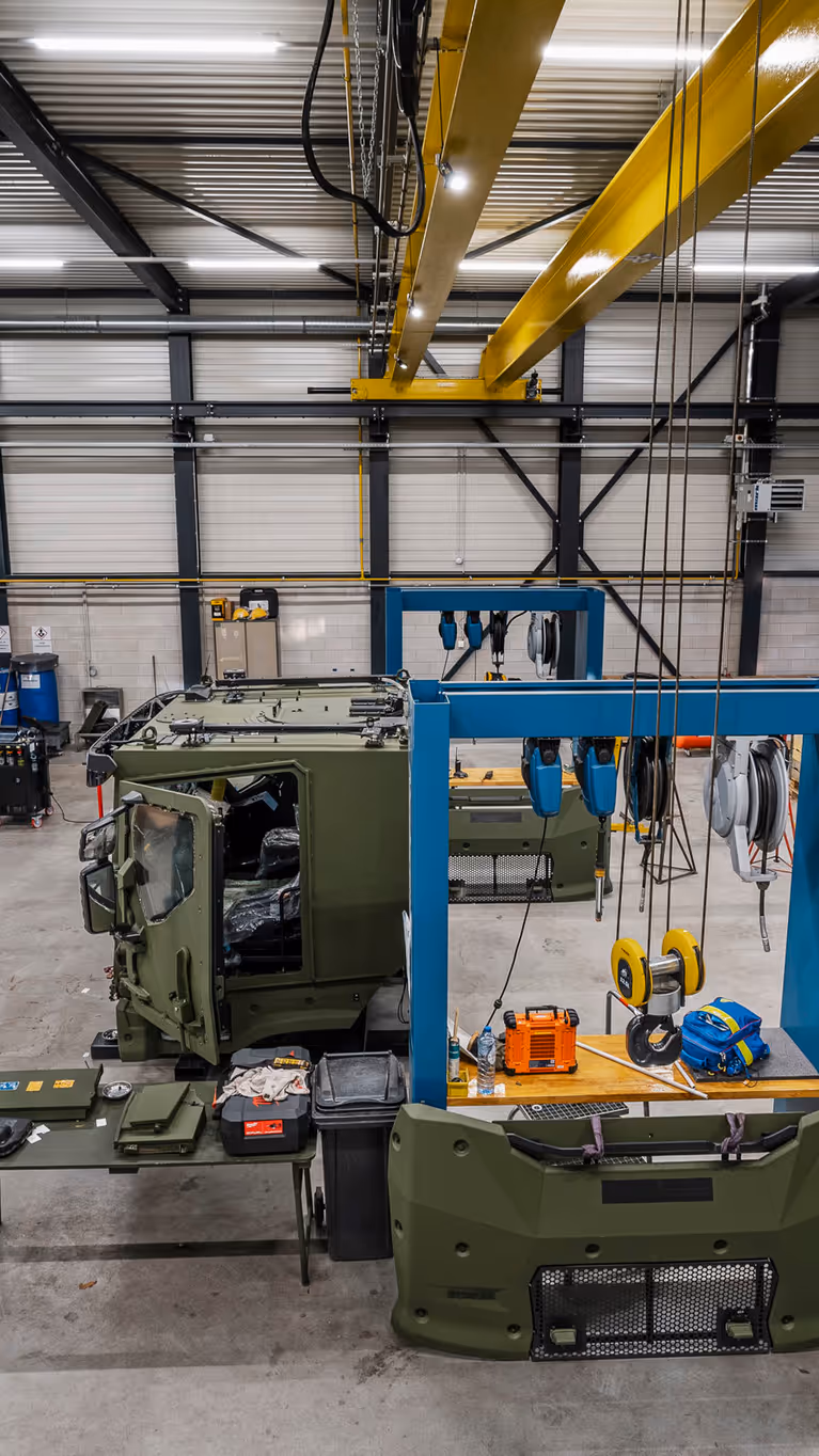 Werkplaats waarin gewerkt wordt aan grote militaire transportvoertuigen.