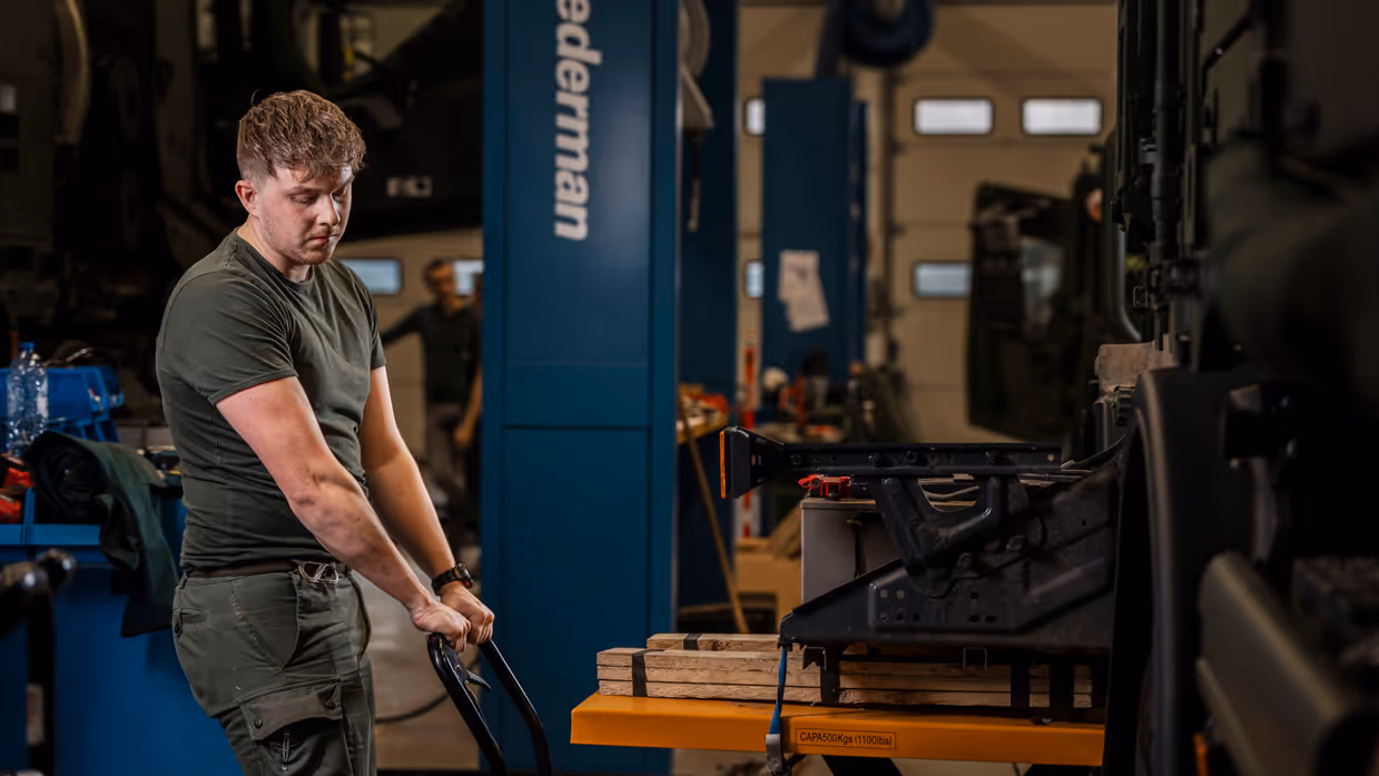 Monteur tilt met krik onderdeel motorblok transportvoertuig op.