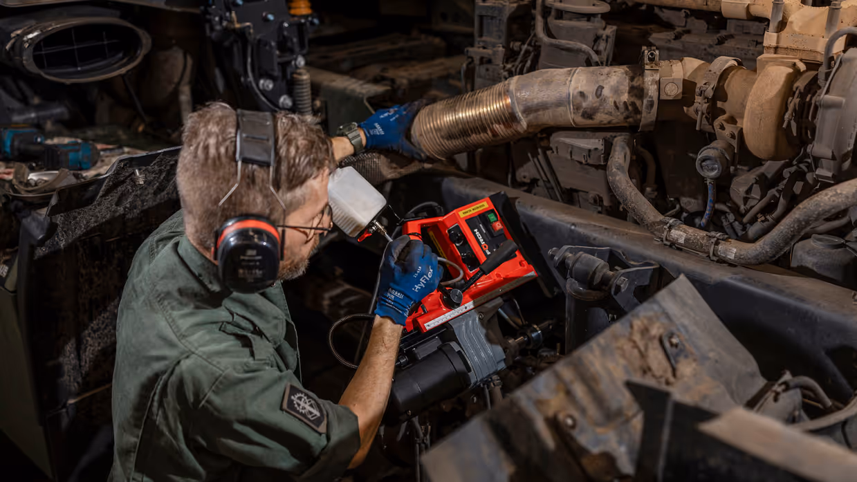 Monteur zit naast motorblok en plaats magnetische kolomboormachine.