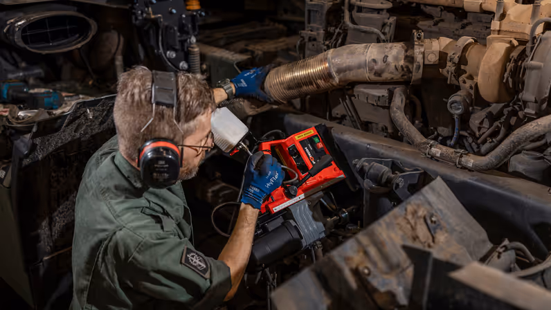 Monteur zit naast motorblok en plaats magnetische kolomboormachine.