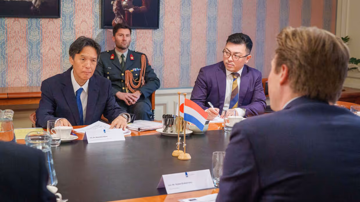 De ambassadeur en de minister overleggen met elkaar aan tafel.