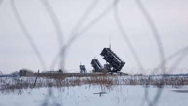 Op de linkerfoto verricht een militair handelingen aan een detectiemiddel met een soort antennes. Rechts staan lanceerinstallaties van de Patriot. 