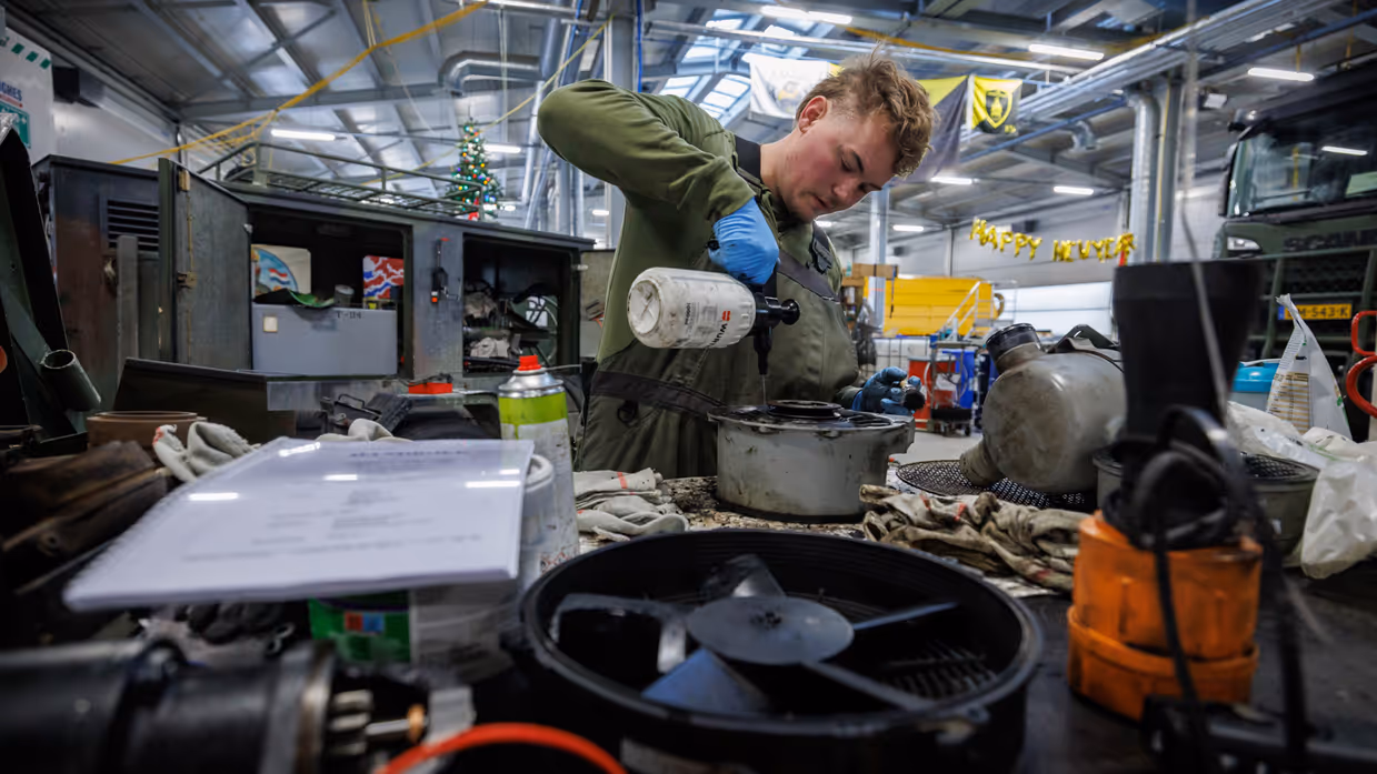 Een monteur druk aan het werk in een grote hal. 