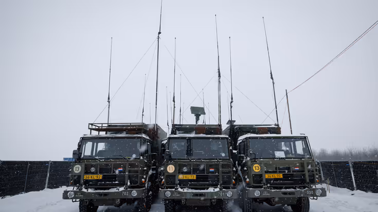 Drie legervrachtwagens van voren gezien. Erboven steken lange antennes uit.