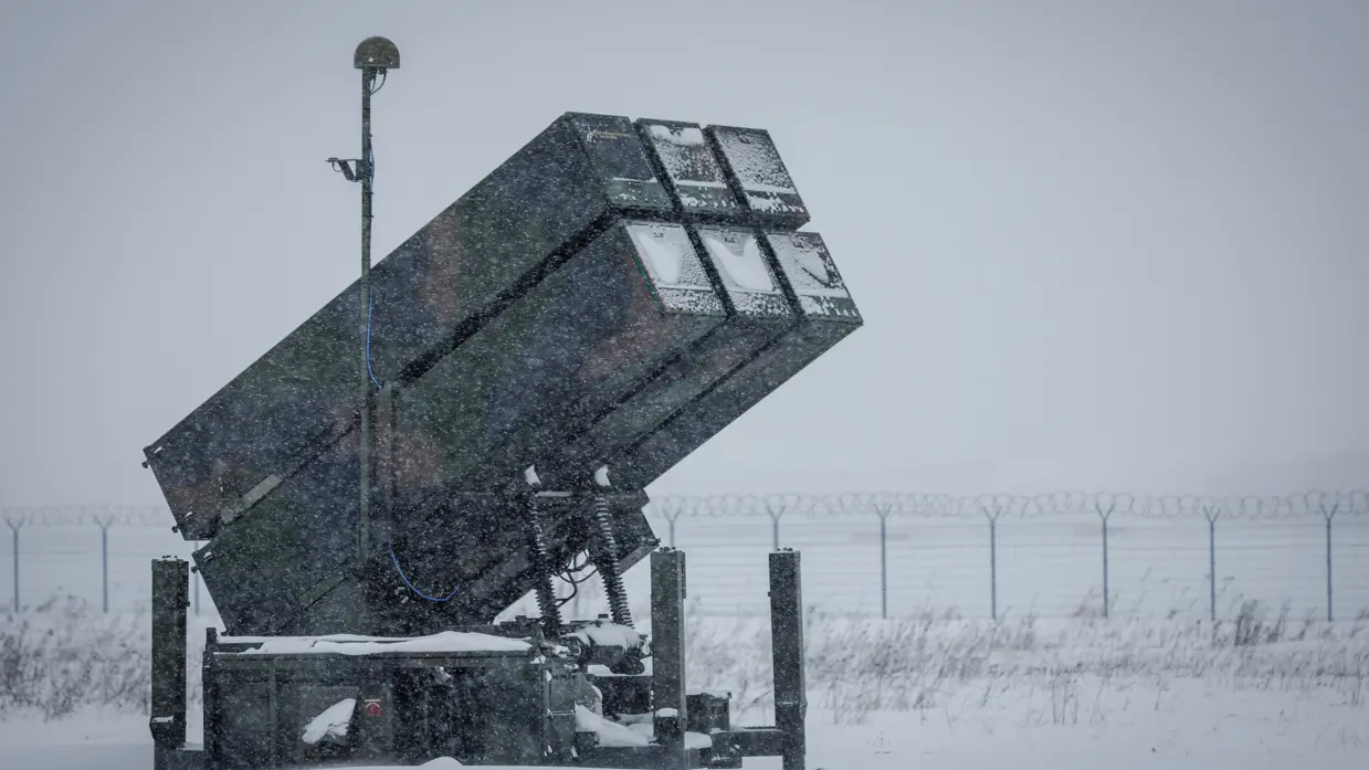 Links een counterdrone-apparaat met grote lenzen. Rechts een NASAMS-lanceerinstallatie in de sneeuw.