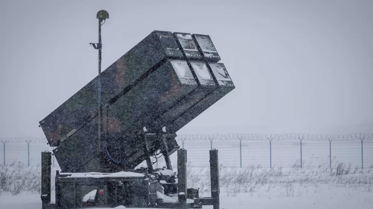 Links een counterdrone-apparaat met grote lenzen. Rechts een NASAMS-lanceerinstallatie in de sneeuw.