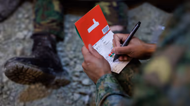 Iemand houdt een rood papiertje met daarop het cijfer 1 beet.