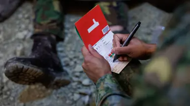 Iemand houdt een rood papiertje met daarop het cijfer 1 beet.