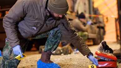 Links zet Rick een geel bordje op de grond met daarop het cijfer acht neer bij een rood tasje. Rick draagt blauwe hopesjes om zijn schoenen. Op de rechterfoto draagt Rick gele, genummerde bordjes en een boekje. Hij heeft blauwe, plastic handschoentjes aan.