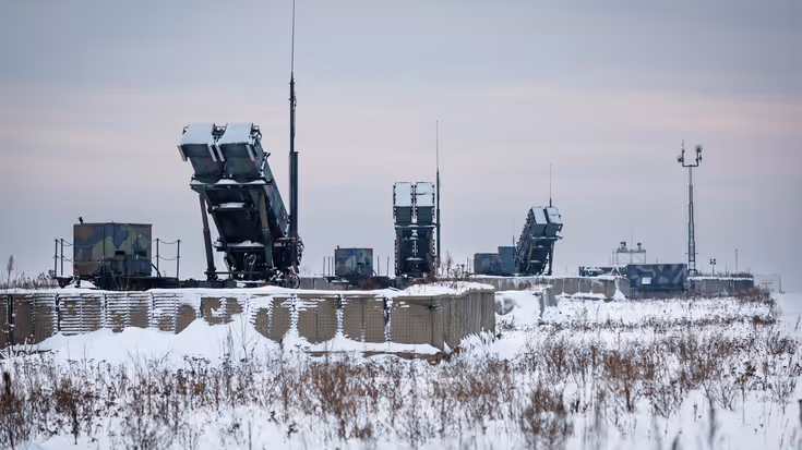 Drie besneeuwde lanceerinrichtingen staan achter obstakels met prikkeldraad.