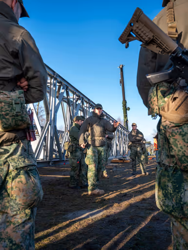 Gewapende militairen luisteren naar uitleg van een commandant.