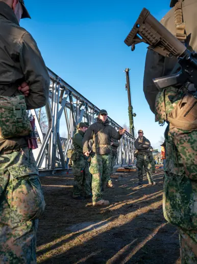 Gewapende militairen luisteren naar uitleg van een commandant.