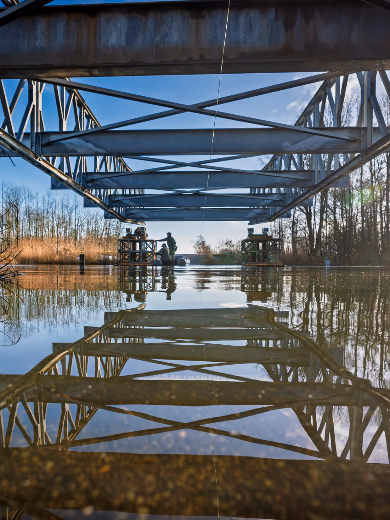 Een foto van het water, waar een deel van de brug overheen hangt.