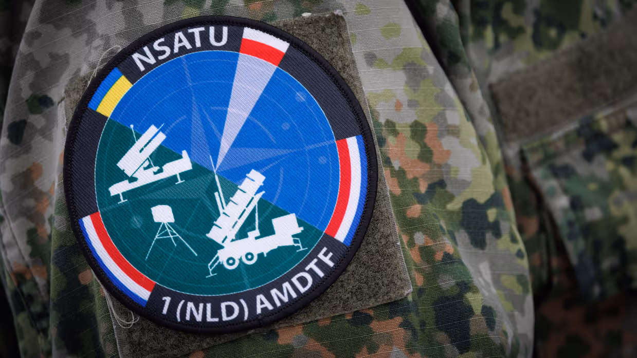 Het logo van NSATU met daarop alle wapensystemen en vlaggen van Oekraïne, Polen en Nederland. 