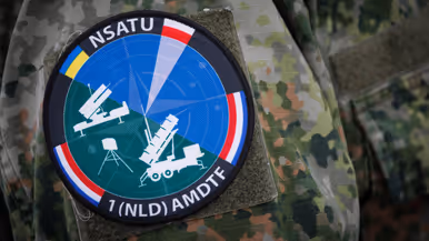 Het logo van NSATU met daarop alle wapensystemen en vlaggen van Oekraïne, Polen en Nederland. 