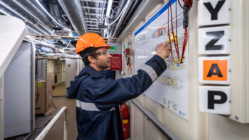 Alt-tekst: Jorren Stierman, senior-engineer Scheepsbouw, bekijkt aan boord van Zr.Ms. Holland een schematische tekening tijdens onderhoudswerkzaamheden.
