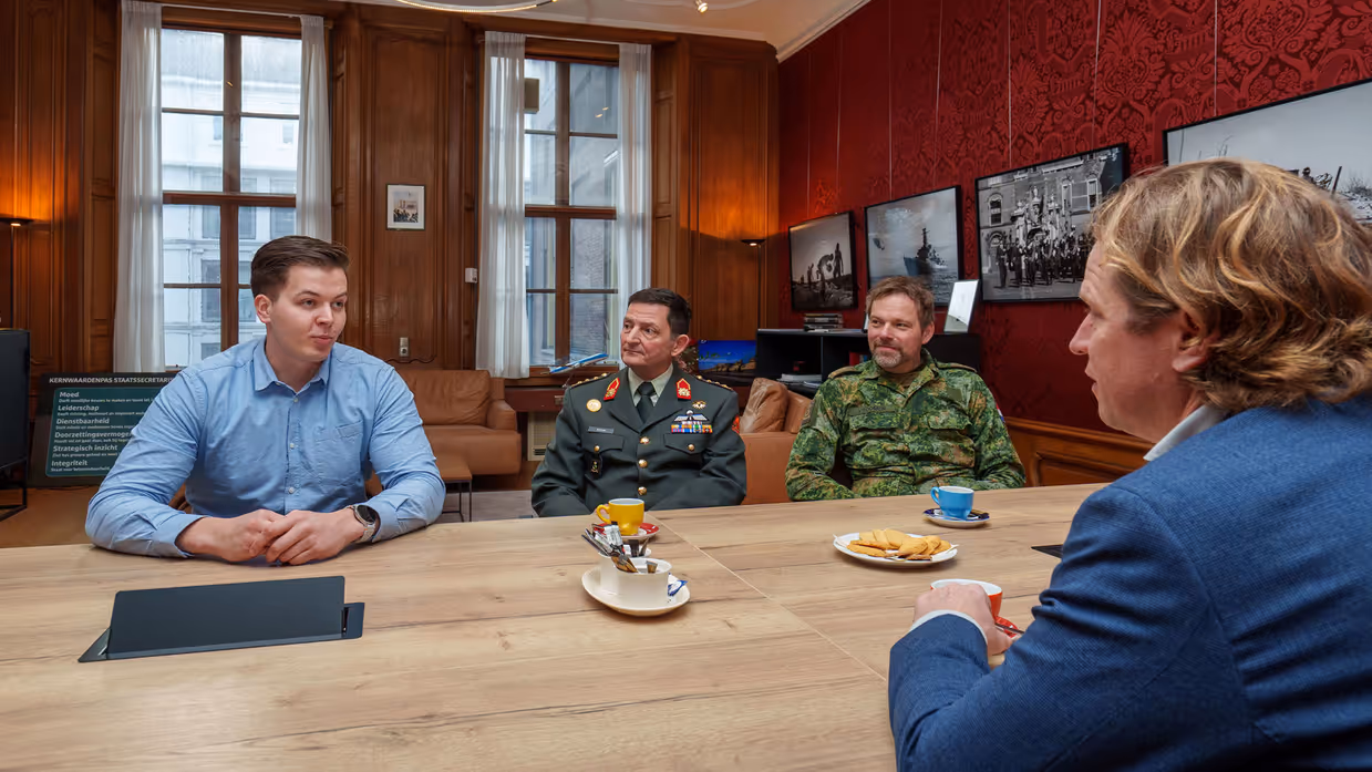 Defensiemedewerker zit aan tafel met 2 hoge militairen en de staatssecretaris.