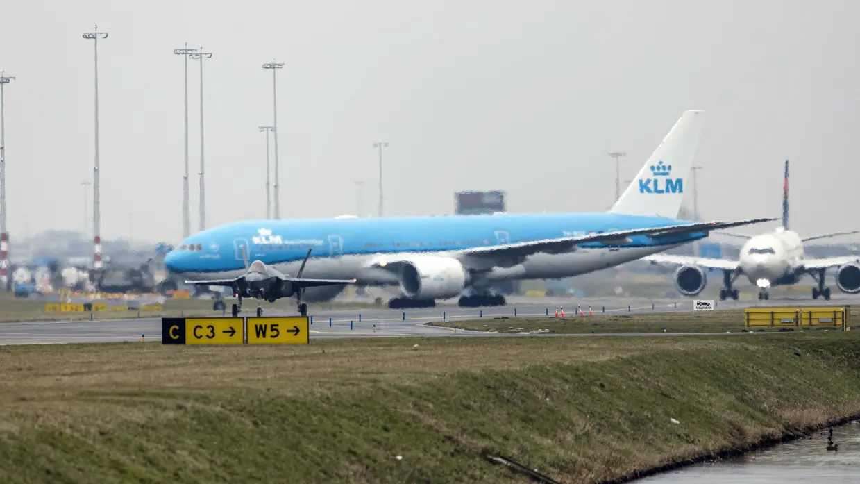 Een taxiënde F-35, met op de achtergrond een blauw passagierstoestel van KLM.