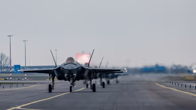 Links F-35’s opgelijnd op de startbaan van Schiphol, rechts: Een tank- en transportvliegtuig A330 MRTT landt op luchthaven Schiphol. De wielen raken net de grond wanneer de foto wordt gemaakt, waardoor er een klein rookwolkje ontstaat.  