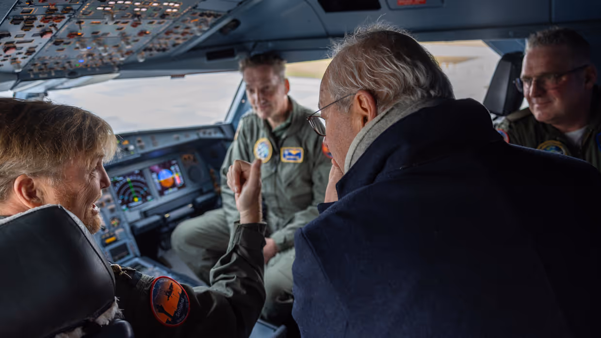 De Koning zit in de cockpit en praat met militairen. 