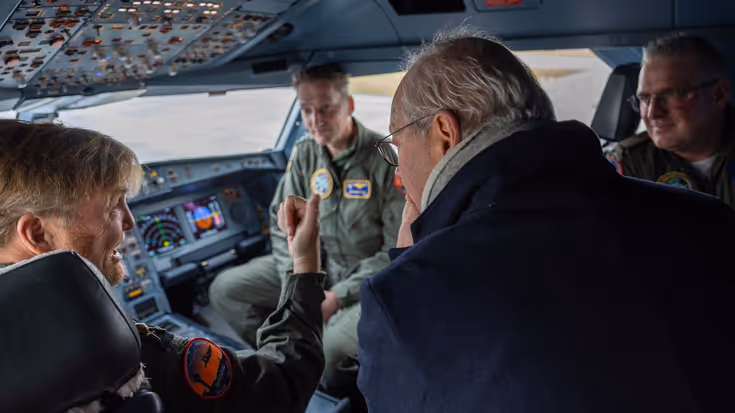 De Koning zit in de cockpit en praat met militairen. 