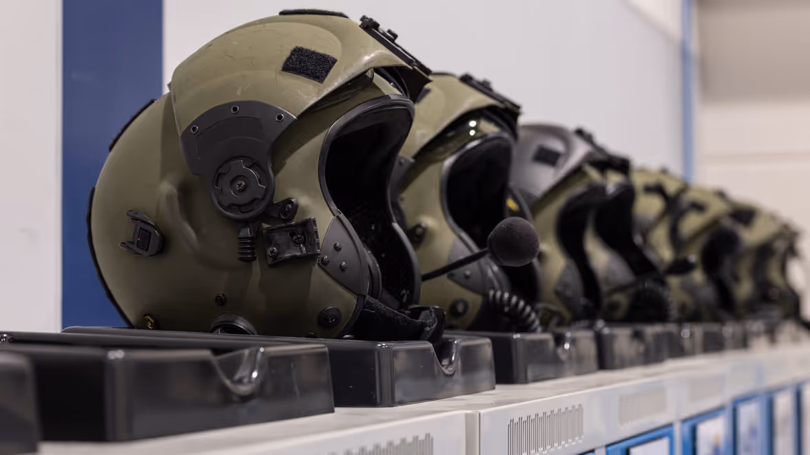 Een rijtje groene vliegerhelmen.