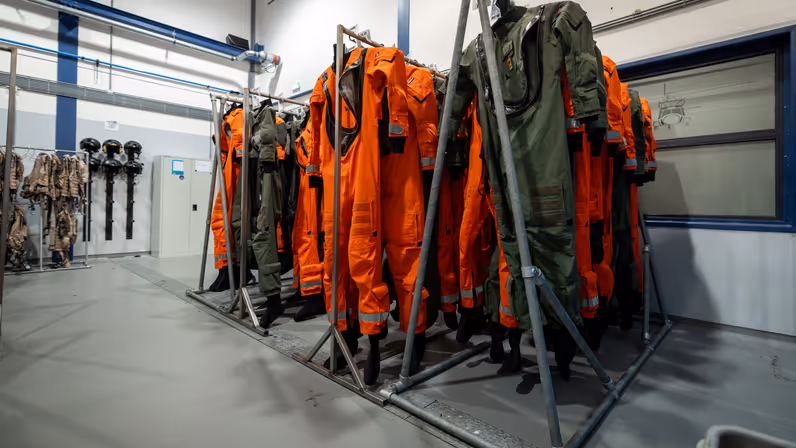 Een rek met oranje vliegoveralls. 