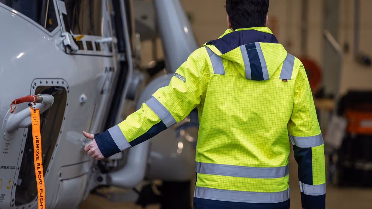 Een NH90 wordt met een speciaal voertuig uit een hangar getrokken.