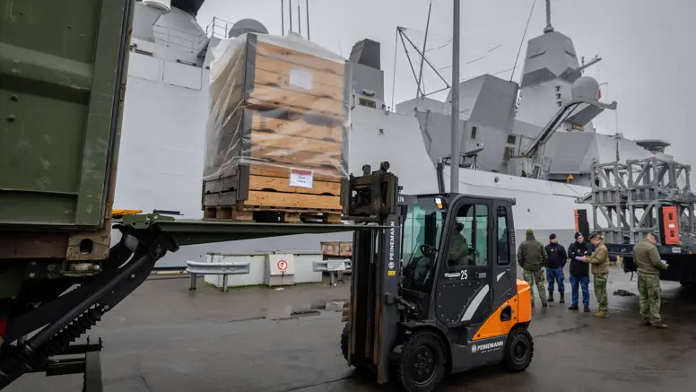 Een vorkheftruck die op de kade een pallet uit een vrachtwagen tilt.