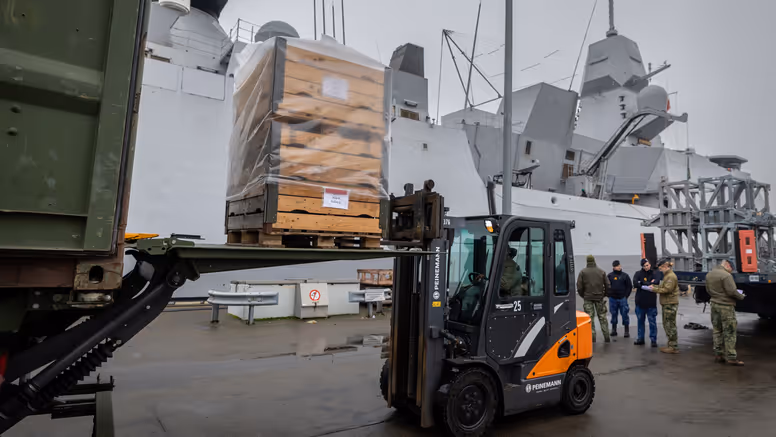 Een vorkheftruck die op de kade een pallet uit een vrachtwagen tilt.