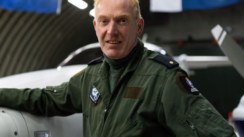 Haiko in vliegoverall staat bij het patrouillevliegtuig in de hangar.