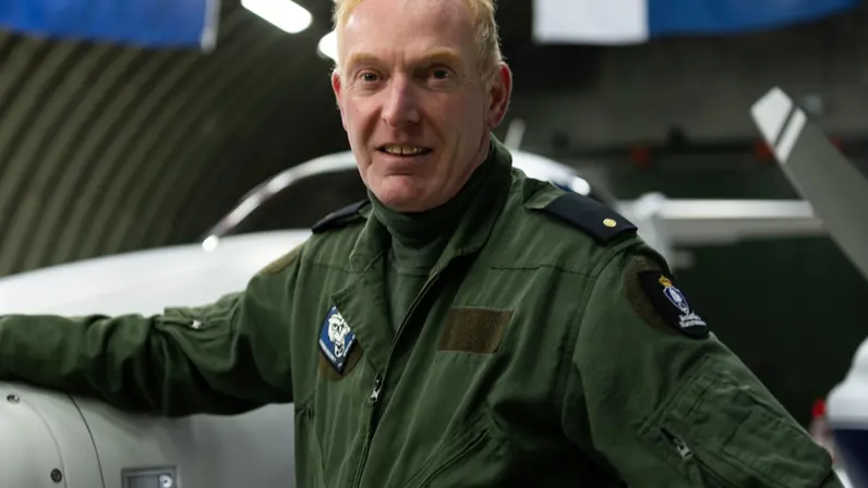 Haiko in vliegoverall staat bij het patrouillevliegtuig in de hangar.
