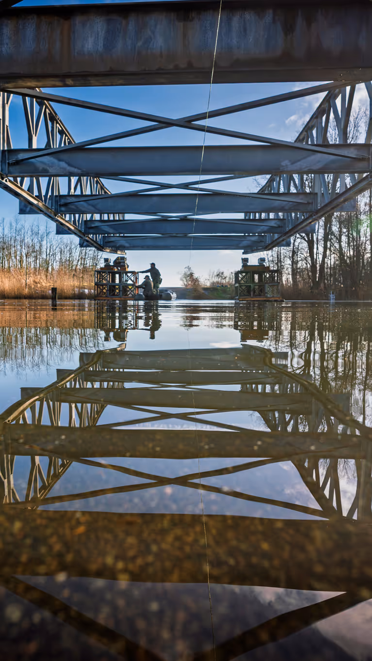 De constructiegenie legt een brug aan over het water.