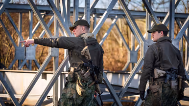 Twee gewapende militairen staan naast een brug.