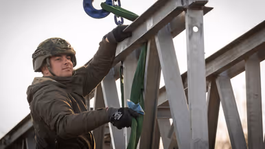 Een militair met een helm op, op de brug.
