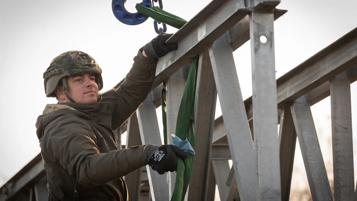 Een militair met een helm op, op de brug.