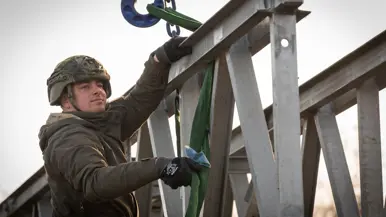 Een militair met een helm op, op de brug.