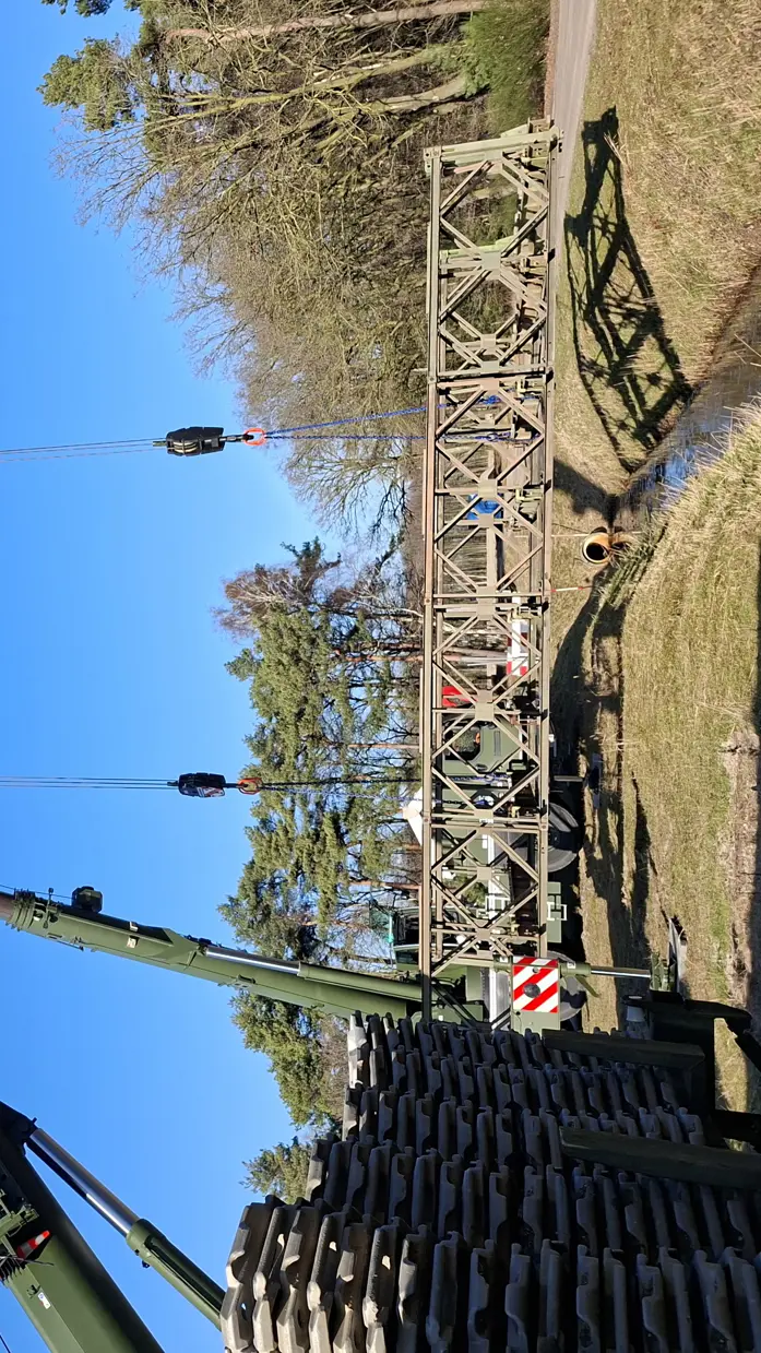Twee hijskranen naast elkaar hijsen materialen op. 