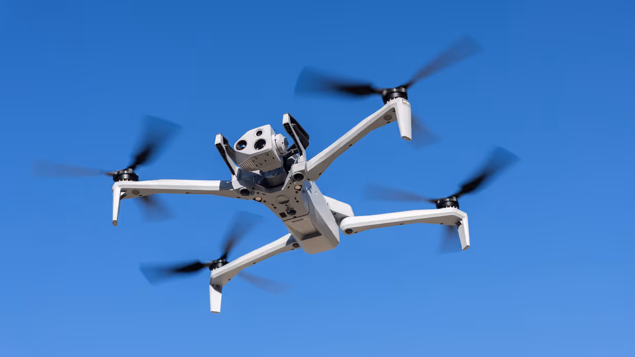 De drone van FO verkeer & visualisatie hangt in de lucht met de camera naar voren gericht en een blauwe lucht op de achtergrond.