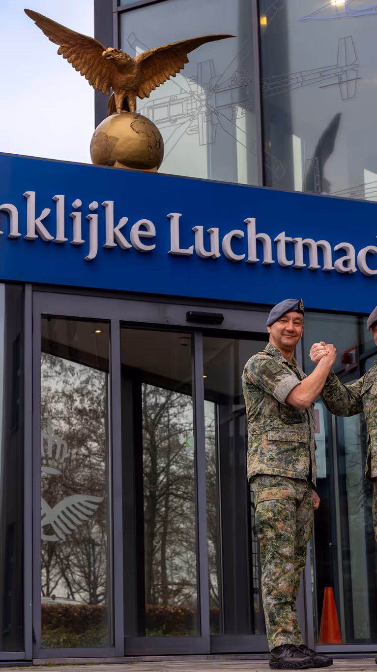  Luchtmachtadjudanten Terry Venhovens en Johan de Rooij schudden elkaar de hand voor de ingang van de Luchtmachttoren in Breda.