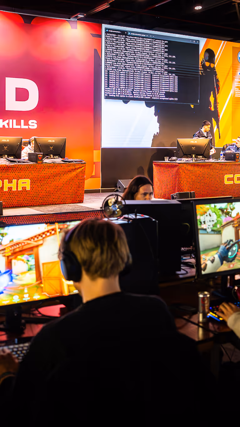 Vier mensen zitten met koptelefoon achter een computer, ze spelen games.