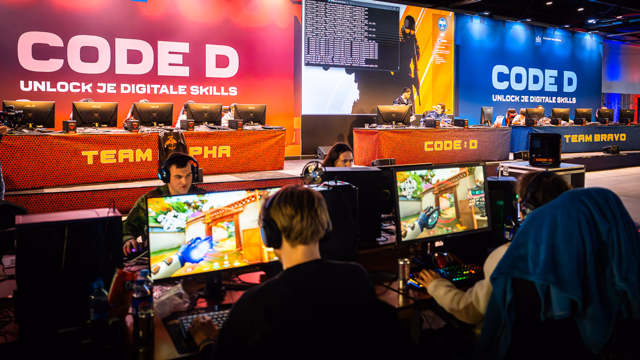 Vier mensen zitten met koptelefoon achter een computer, ze spelen games.