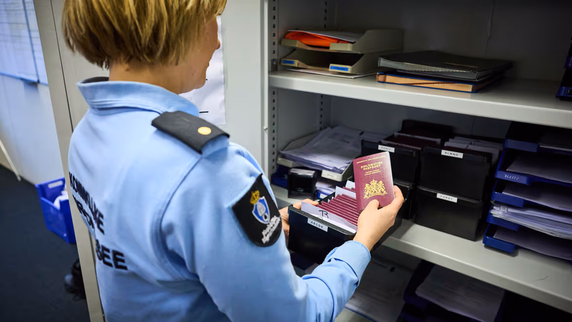 Adjudant Carolien bladert door de diplomatieke paspoorten die de afdeling Support in bewaring heeft.