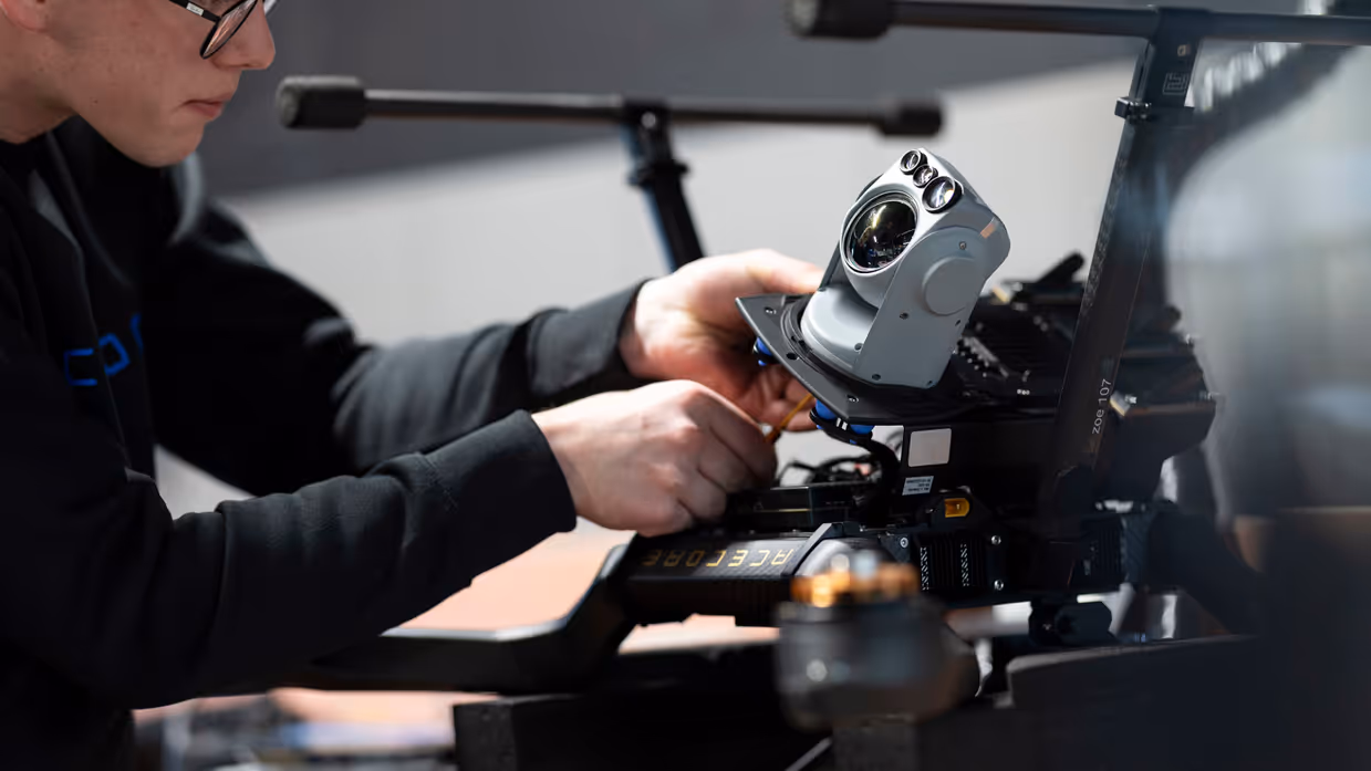 Een medewerker van Acecore schroeft een camera onder een drone.