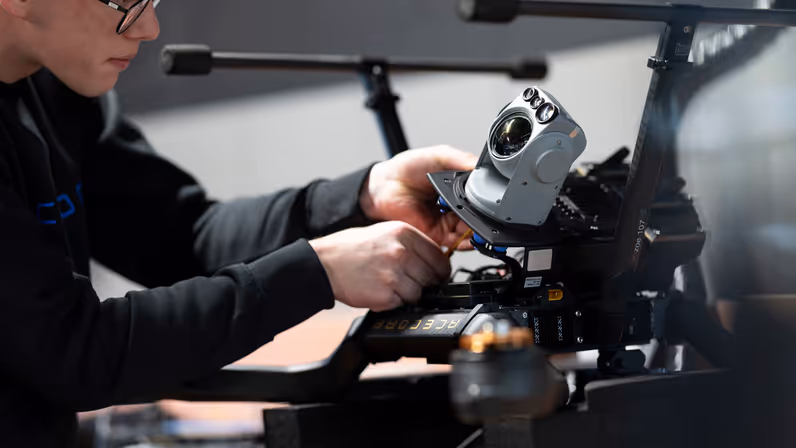 Een medewerker van Acecore schroeft een camera onder een drone.