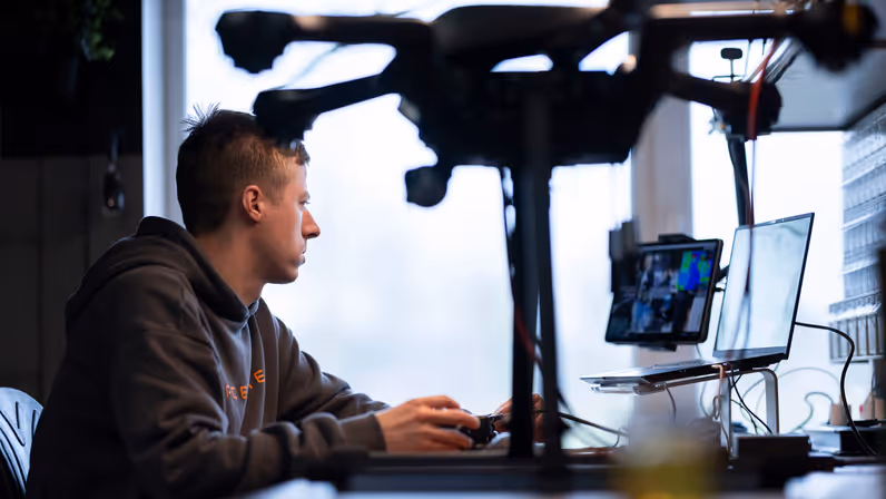 Een medewerker van Acecore zit aan zijn bureau, op de voorgrond een drone.